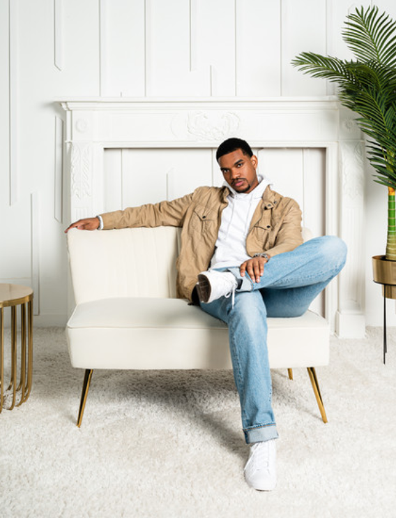 Jermaine Robinson sitting on a white couch with his arm across the back and his legs crossed.